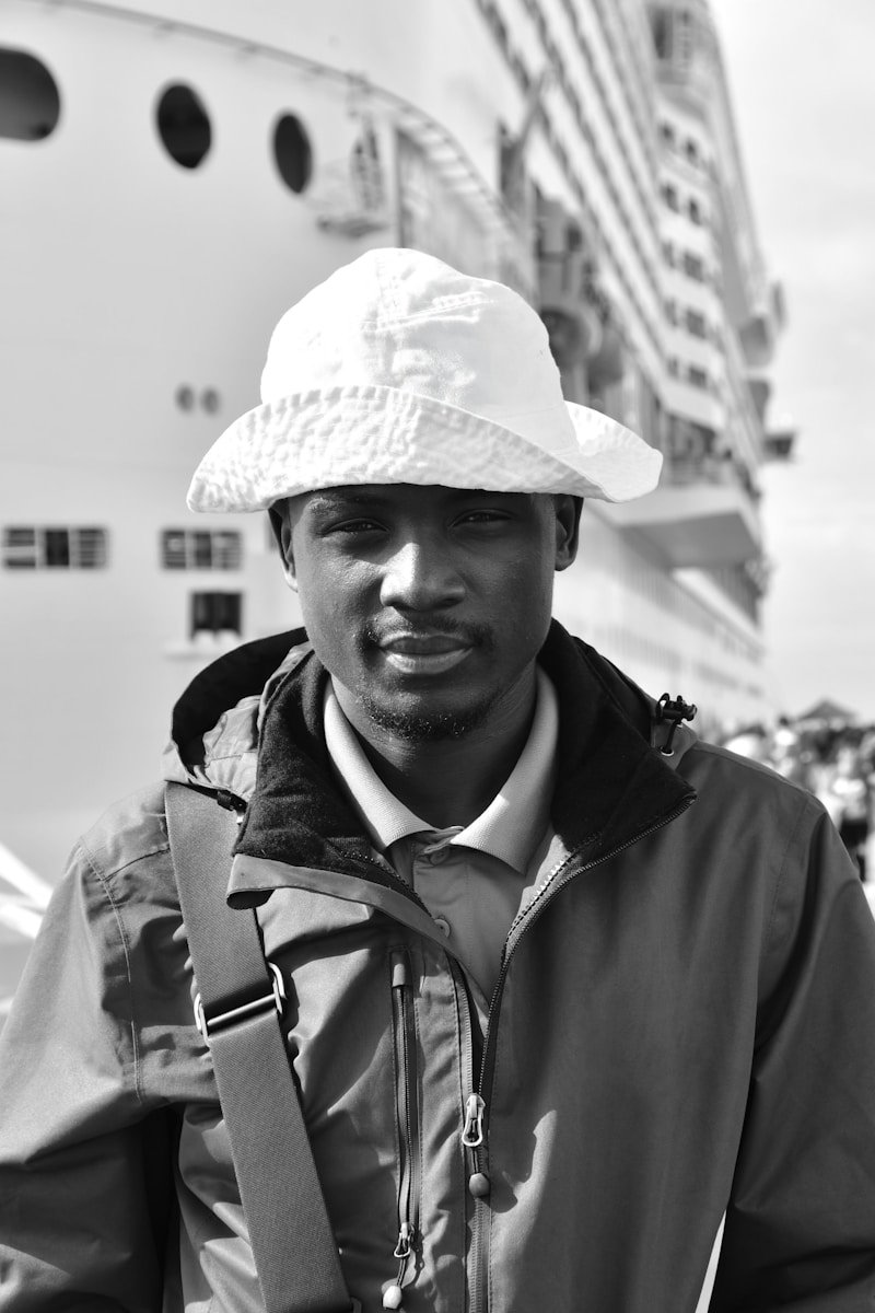 A man poses in front of a cruise ship.